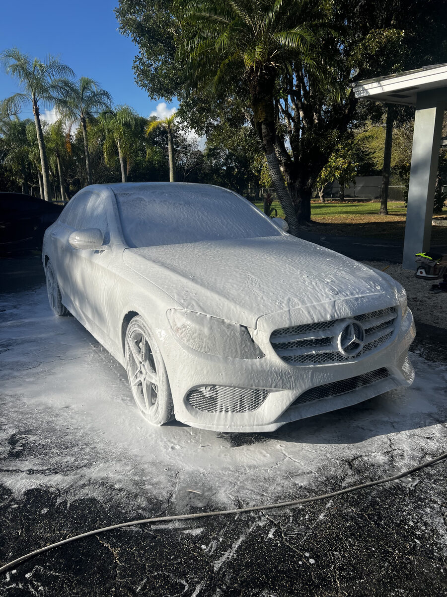 White Mercedes C-Class covered in foam during car wash pre-treatment